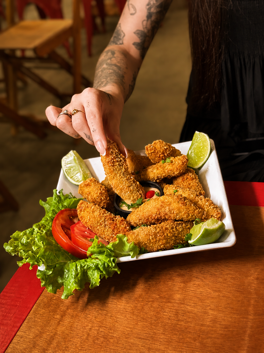 Porção de tilápia empanada servida no Tigrão com molho, limão e salada